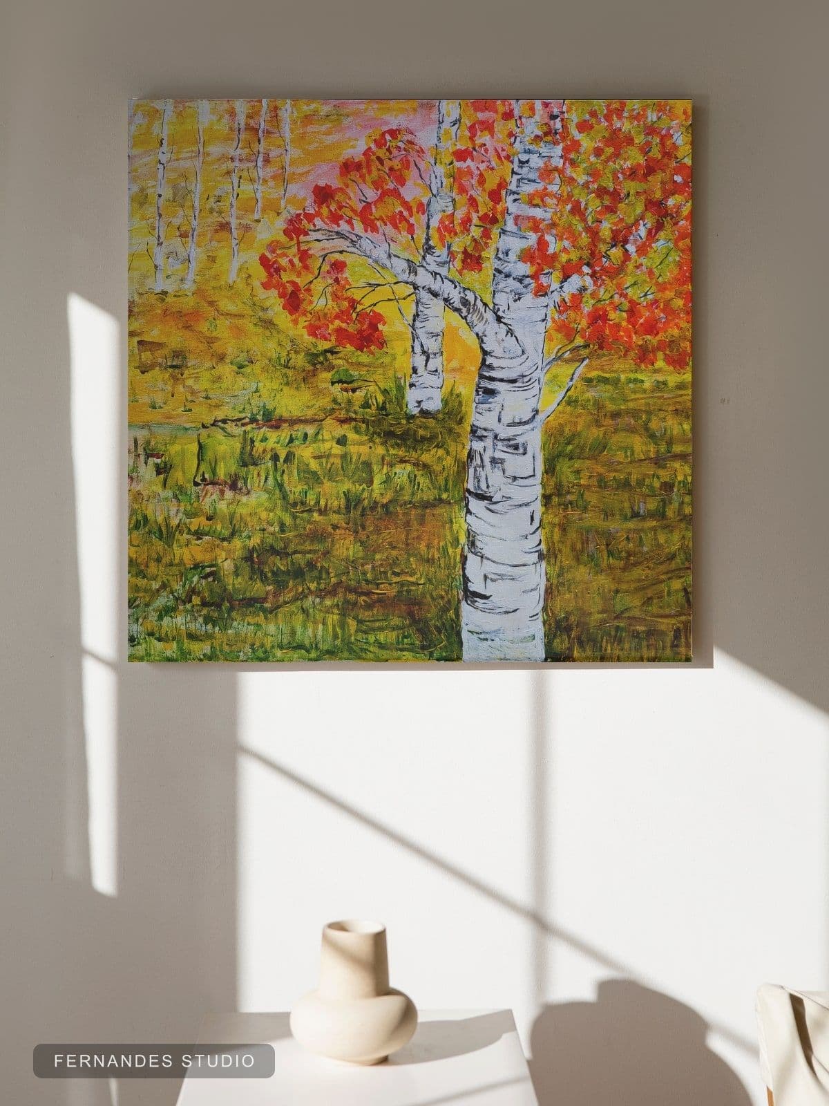 Birches at Sundown — two birch trunks with autumn leaves reflected in still water at golden hour, framed on a gallery wall